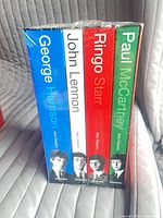 Colour-coded spines of four sealed volumes in shrink-wrap