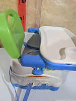 Side view showing removable tray, green backrest, blue base, and safety straps