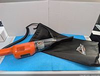 Side view of Armor All handheld car vacuum, storage bag, and background for size reference