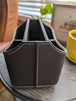 front view of dark brown faux leather caddy showing white stitching and compartment openings