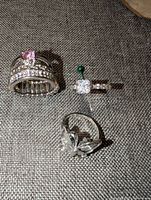Three silver-tone cubic zirconia rings displayed on fabric