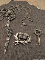 All five Celtic jewellery pieces laid out: two pendant necklaces and three brooches