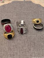 Group of seven men's rings arranged on grey fabric