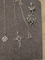 Three necklaces and two brooches arranged on fabric background