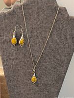 Necklace and earrings displayed on bust, showing stone color, metal tone, and design details