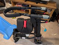 Side view of black Nexus rollator walker showing frame, seat, handles, wheels, and red nexus folding strap