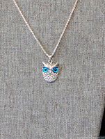 Owl head pendant necklace with blue eyes displayed on fabric bust