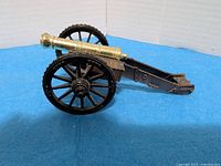 Side view of brass-tone barrel and black carriage cannon model