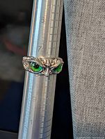Front view of owl ring on ring mandrel showing green eyes and CZ detail