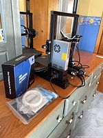 Overall view of partially assembled Ender-3 Pro printer, power supply, wiring, accessory box on dresser