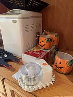 Breadmaker, pumpkin mugs, mandoline box, bottle opener, mini chopper visible