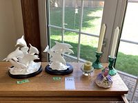 Overall lot showing both Lenox dolphin figurines, Royal Doulton Monica figurine, two green candle holders with white candles, clear votive with green candle