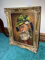 Framed oil portrait of bearded man wearing green hat with feather, leaning against wall