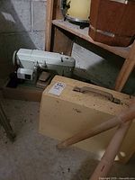Sewing machine in base beside hard carrying case and foot pedal visible
