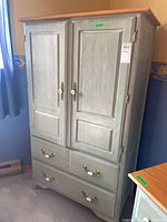 Full view of green painted wood armoire with two doors and two drawers