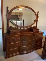 Front view of dresser with attached oval mirror showing overall design and drawer layout