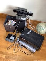 Group shot showing receiver, VHS/DVD combo, speakers, bin of Wii games, answering machine, cables