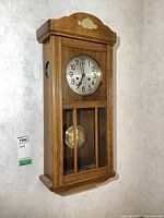 Front view of wooden pendulum wall clock hanging on wall, door closed