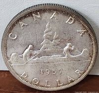 Reverse side of 1957 Canadian silver dollar showing canoe design and date