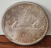 Reverse of 1965 Canadian silver dollar showing CANADA, canoe design and date