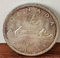 Reverse of 1965 Canadian silver dollar showing Voyageur design and date