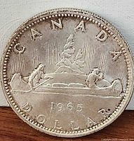Reverse of 1965 Canadian silver dollar showing voyageur canoe design and date