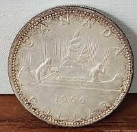 Reverse of 1966 Canadian silver dollar showing canoe design and date