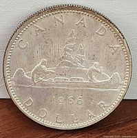 Reverse of 1966 Canadian silver dollar showing canoe design and date