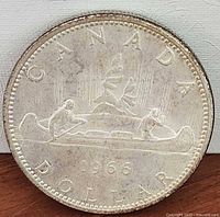 Reverse of 1966 Canadian silver dollar showing canoe design and date