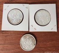 Three Canadian 50-cent coins, two in holders, one loose