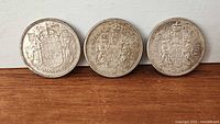 Three Canadian 50-cent coins lined up reverse side showing dates 1958, 1960, 1962