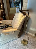 Full view of brass floor lamp beside chair