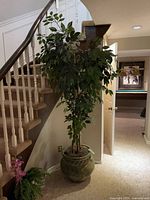 Full view of faux tree in planter beside staircase