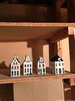 Four KLM Delft Blue miniature ceramic houses lined on shelf