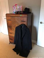 Overall view showing jacket hanging and hat, clutch, scarves on dresser