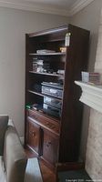 Full view of tall wooden shelving unit showing open shelves, drawer, and lower cabinet