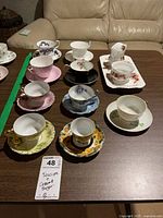 All nine teacup sets and cream/sugar set arranged on table
