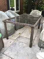 Full view of wicker patio table with glass top