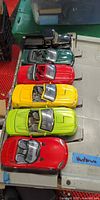 Six brightly colored convertible die-cast cars lined up on plastic lid