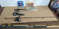 Overall view showing two rods, tackle box, knives, mounted reel