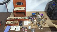 overview of entire lot on table: jewelry box, loose jewelry pile, carded pieces