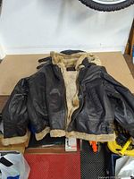 Front view of black leather coat with hood and shearling lining