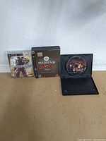 Wide view showing three PS3 game items: sealed Madden NFL 09 collector’s box, Transformers game case, open case with Folklore disc.