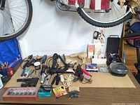 Overall view of table with hair styling tools, dryer, clipper, manicure kits, first-aid pads, boxed cosmetics, hair ties