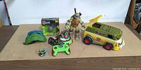 Full lot showing van, Donatello figure, boxed RC toy, plug-and-play game, mask and disc
