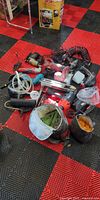 Pile of assorted corded power tools, respirator mask and hose on floor