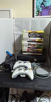 Full lot view with console, controllers, power supply, AV cable, and stack of game cases
