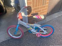 Full side view of white 16-inch kids bike with colourful graphics and split-colour tyres