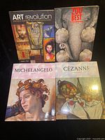 Four art books laid out together