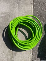 Coiled bright green garden hose on pavement